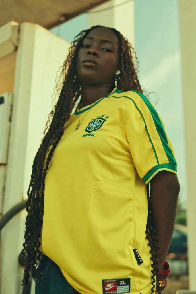 Portrait of a woman wearing a yellow Brazilian soccer jersey, standing confidently outdoors.