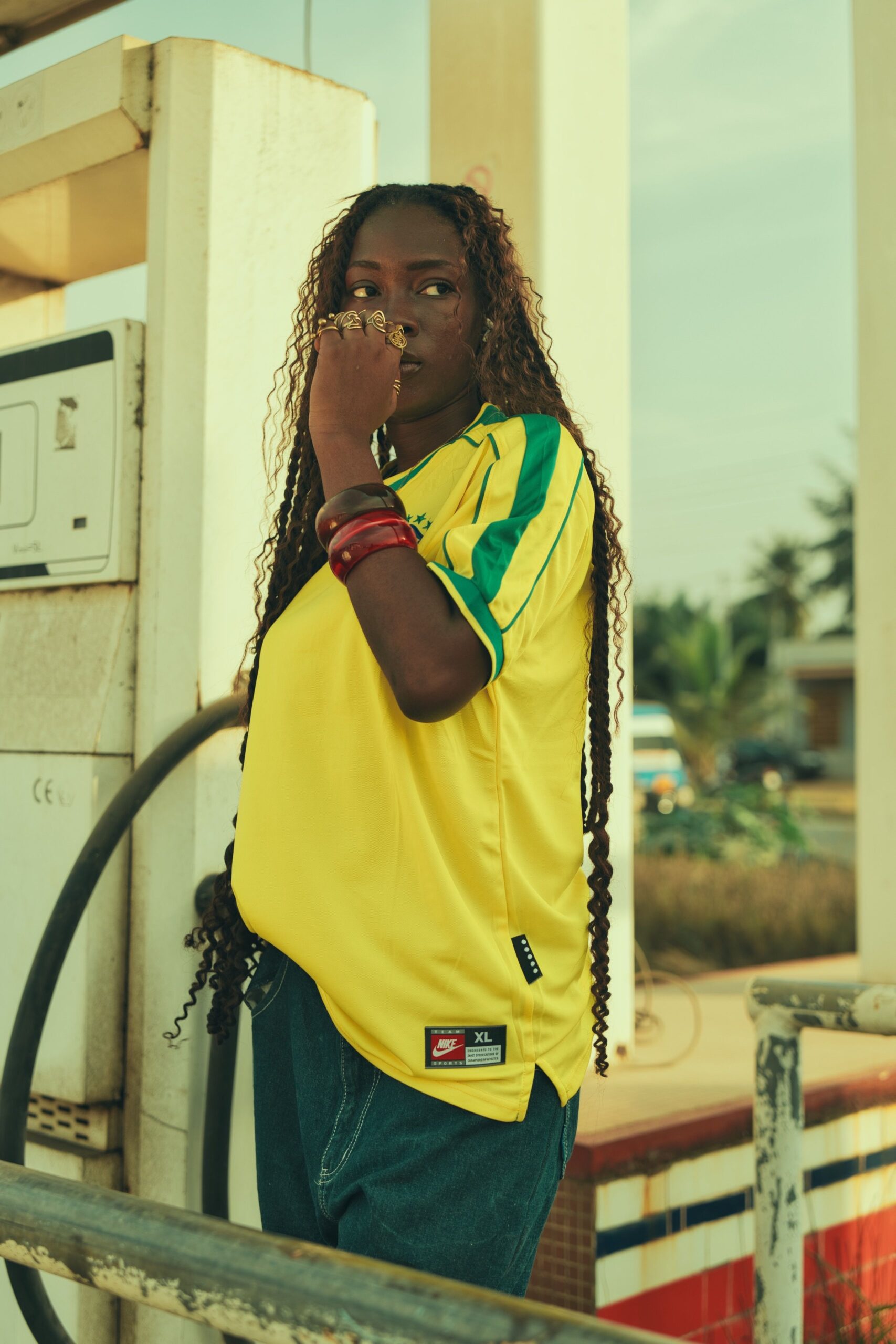 Home African woman in yellow jersey at a retro fuel station. Summer vibe.